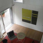 Pohled z galerie na jednací prostor atelieru, na stěnách výtvarné umění ve stylu abstraktní geometrie.
