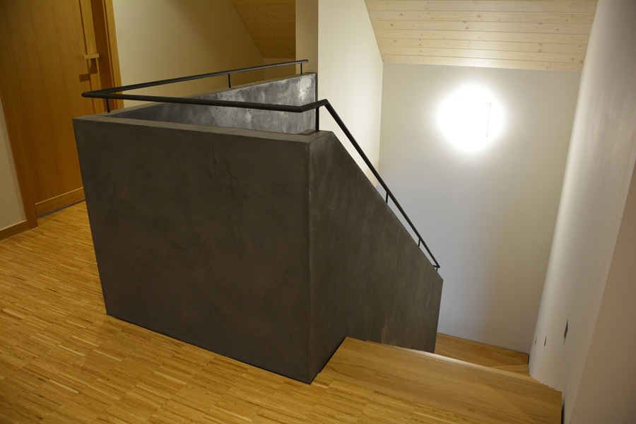 Dřevěné schodiště doplněné zděným zábradlím zvýrazněným betonovou stěrkou.